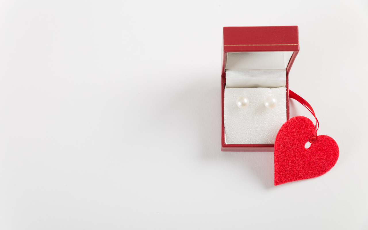 Красная коробка с жемчужными сережками с сердцем на красном фоне
