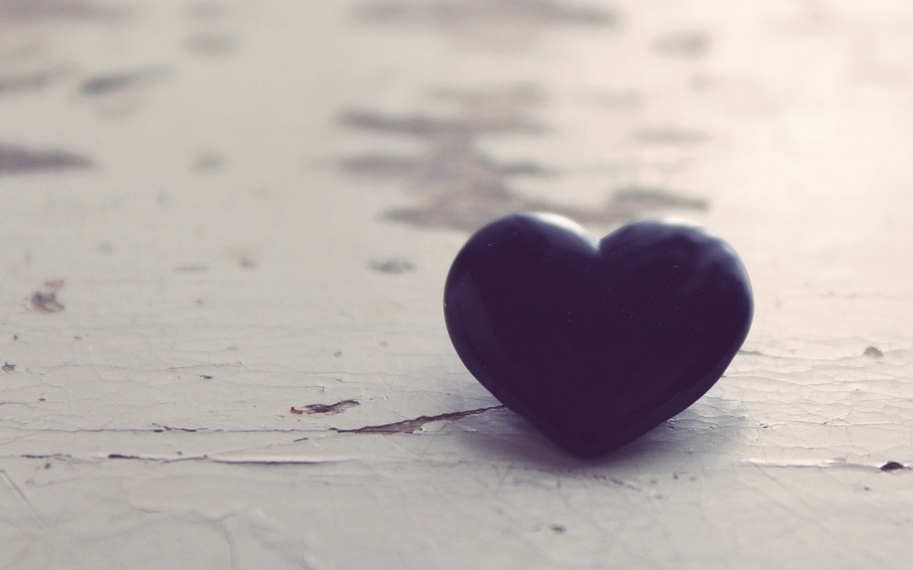 Черное каменное сердце на деревянной поверхности 