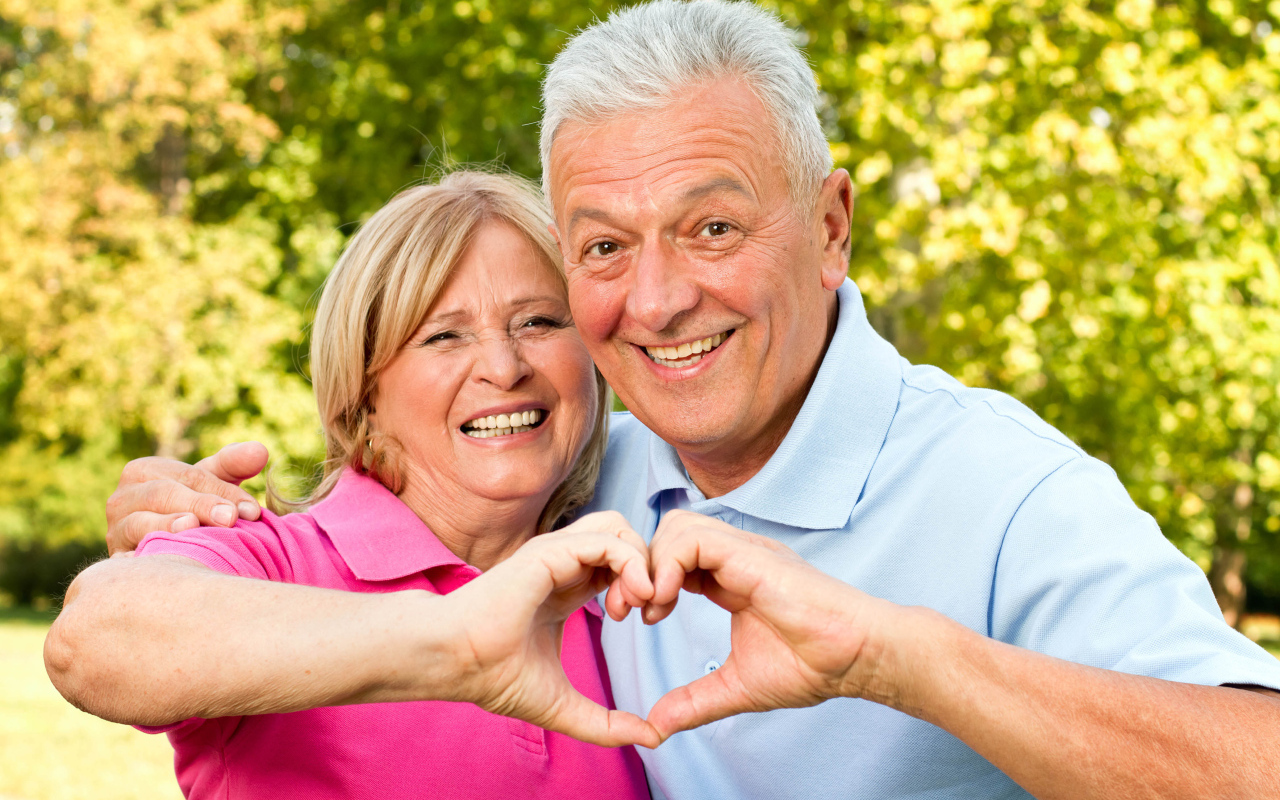 Улыбающаяся пара делает сердце руками