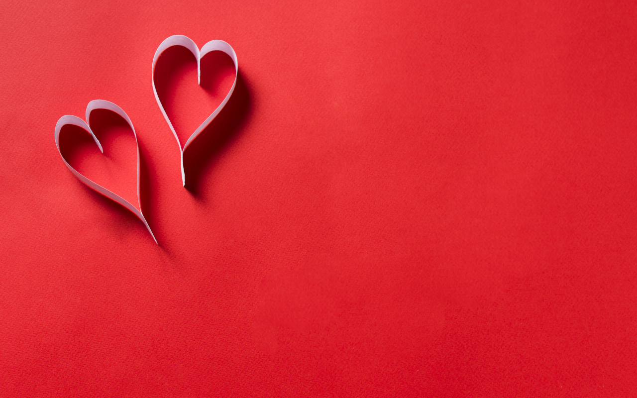 Two white paper hearts on a red background