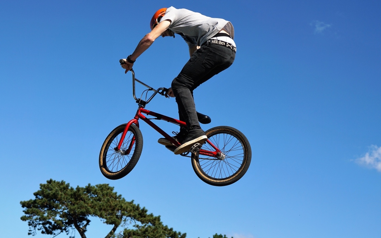 Мужчина делает прыжок на велосипеде на фоне неба