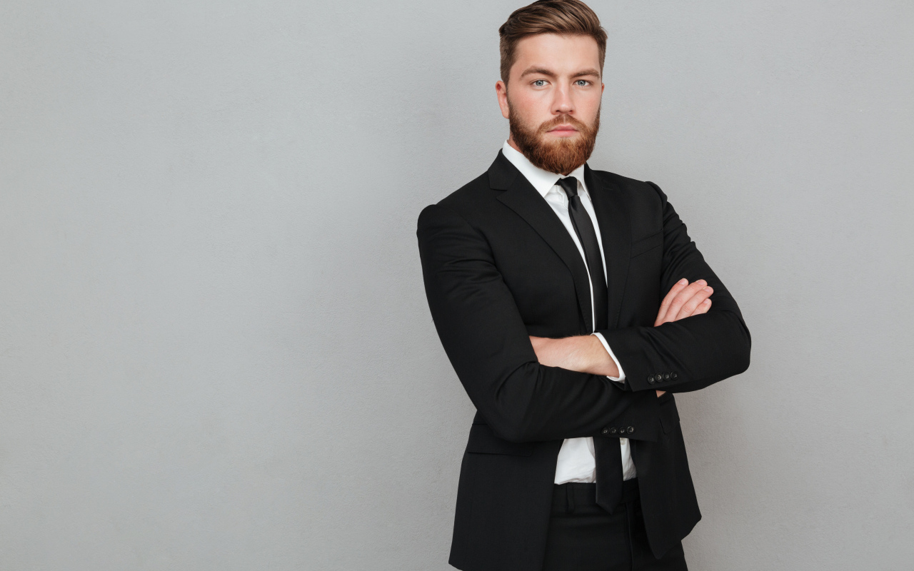 Деловой стильный мужчина в черном костюме на сером фоне