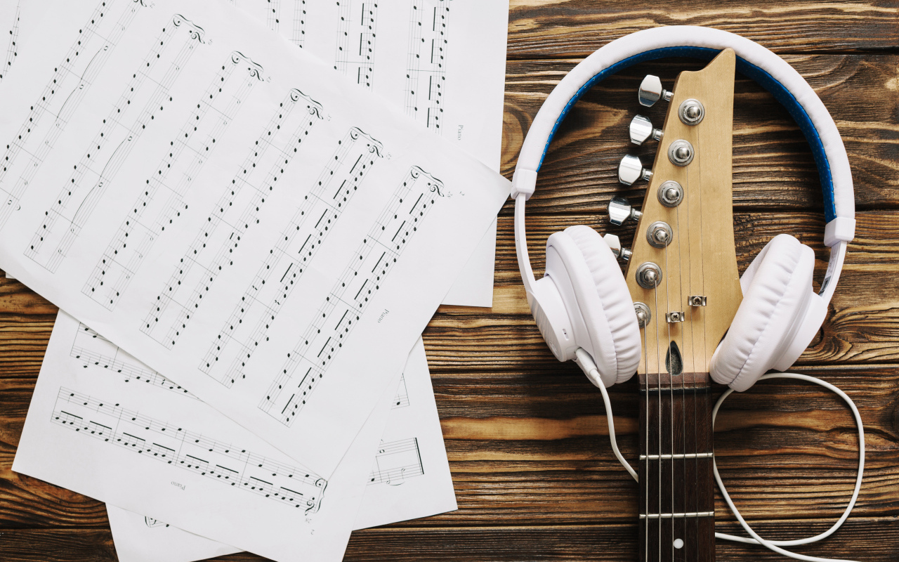 Ноты, наушники и гитара на столе