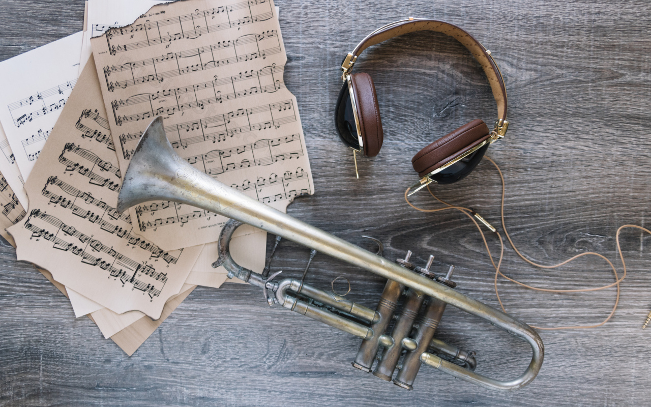 Старые ноты, наушники и труба на столе
