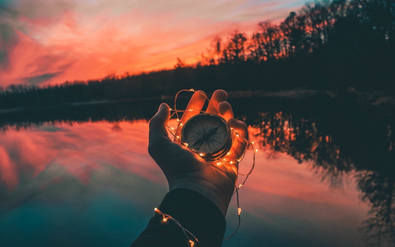 Компас с гирляндой в руке у реки