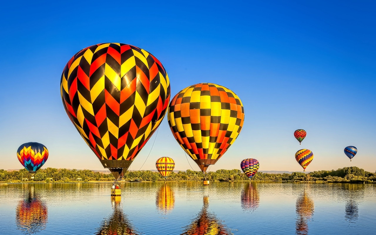 Большие воздушные шары над водой на фоне голубого неба