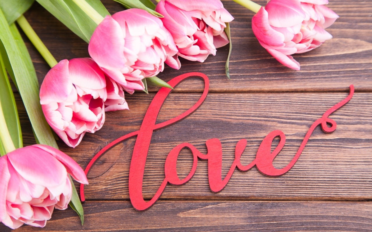 Букет розовых тюльпанов с надписью любовь на деревянном столе