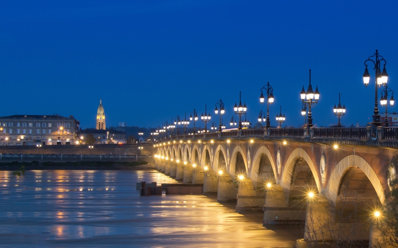 Красивый светящийся мост через реку ночью 