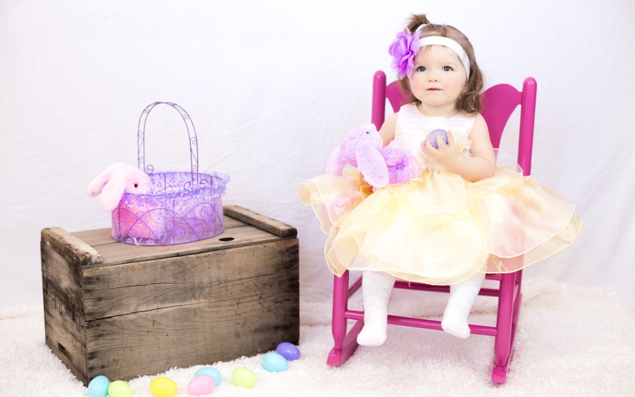 Девочка в красивом платье сидит на стуле 