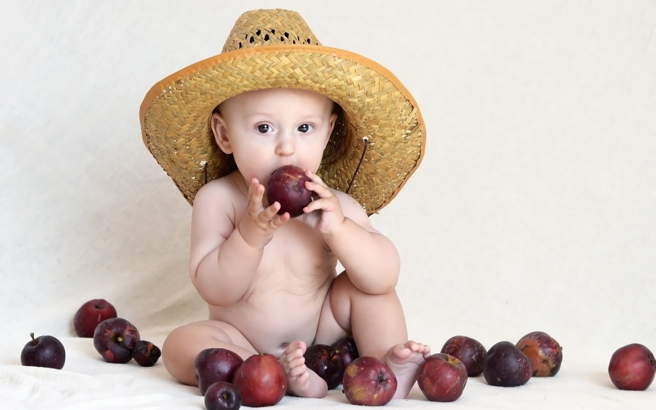 Малыш в шляпе грызет яблоки