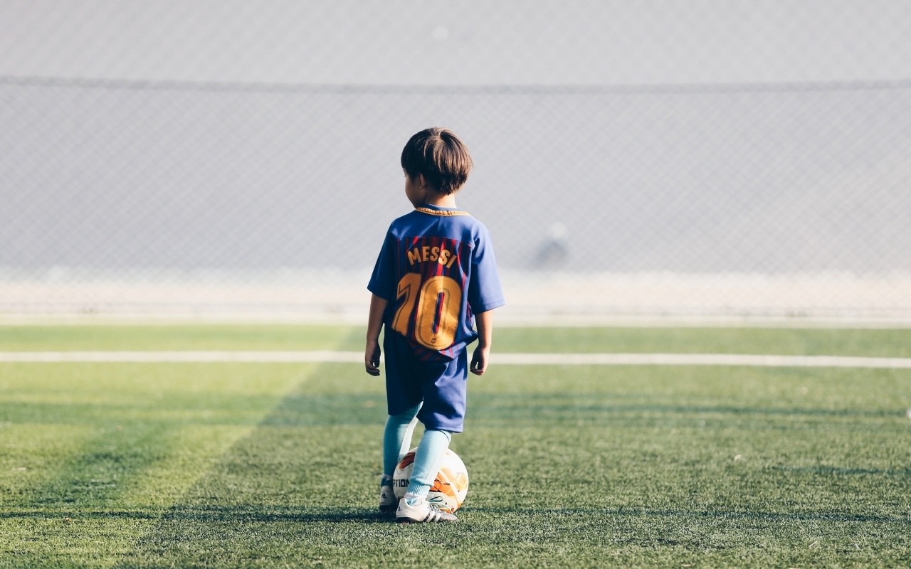 Мальчик футболист с мячом на поле