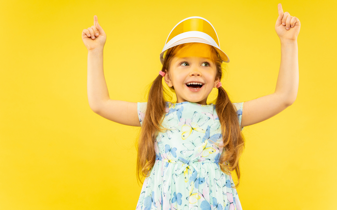 Веселая девочка в платье на желтом фоне