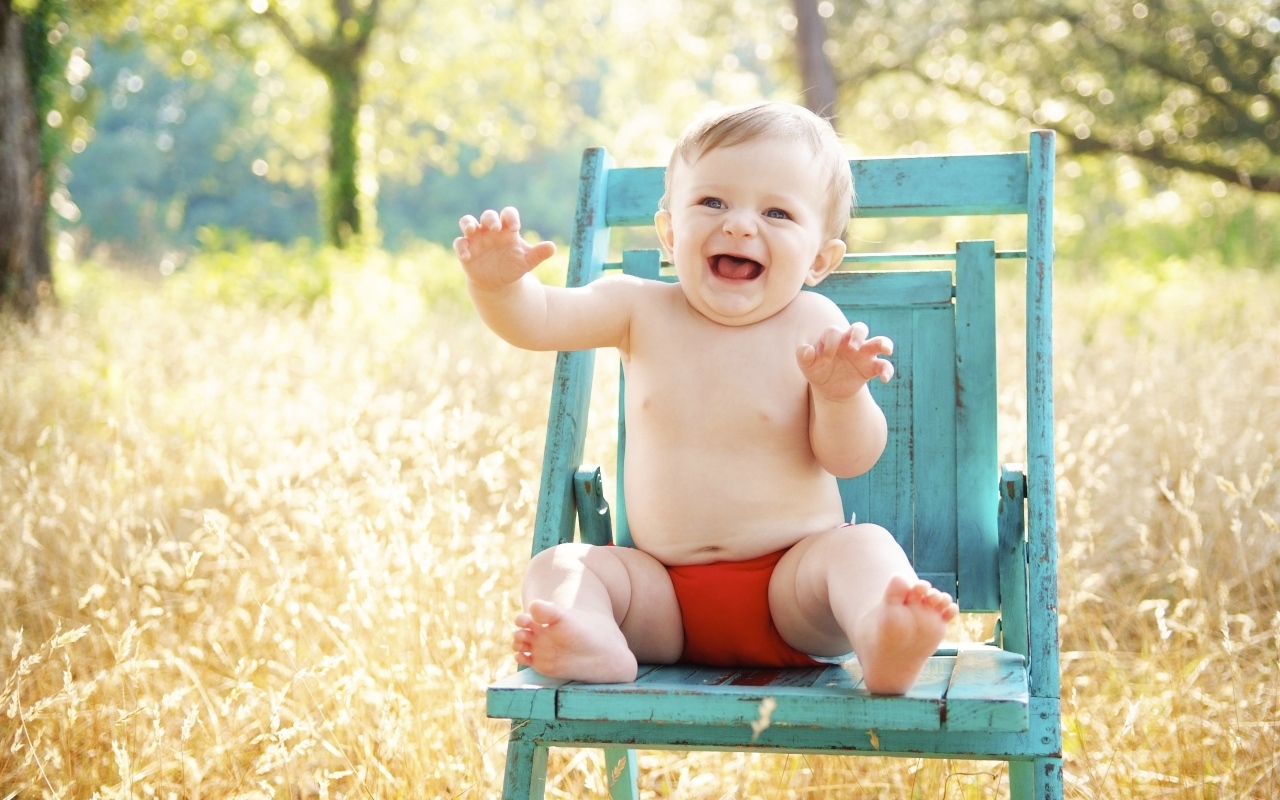 Веселый маленький мальчик в кресле 