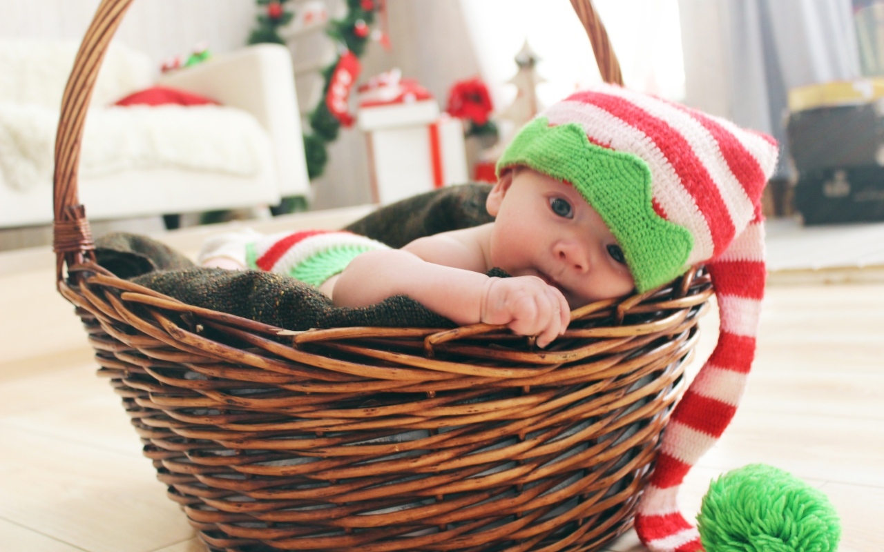 Милый малыш в большой вязаной шапке в корзине