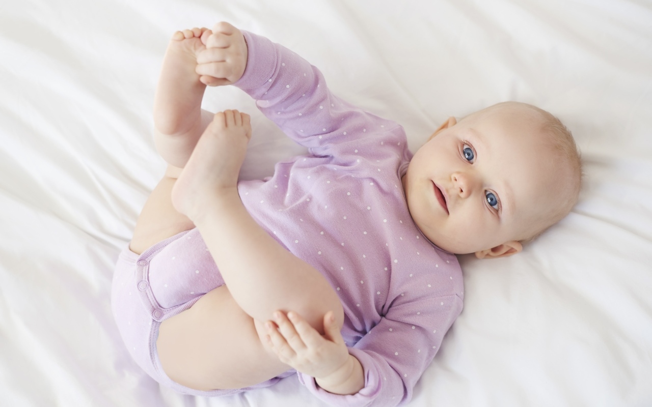 Милый голубоглазый малыш на белом покрывале