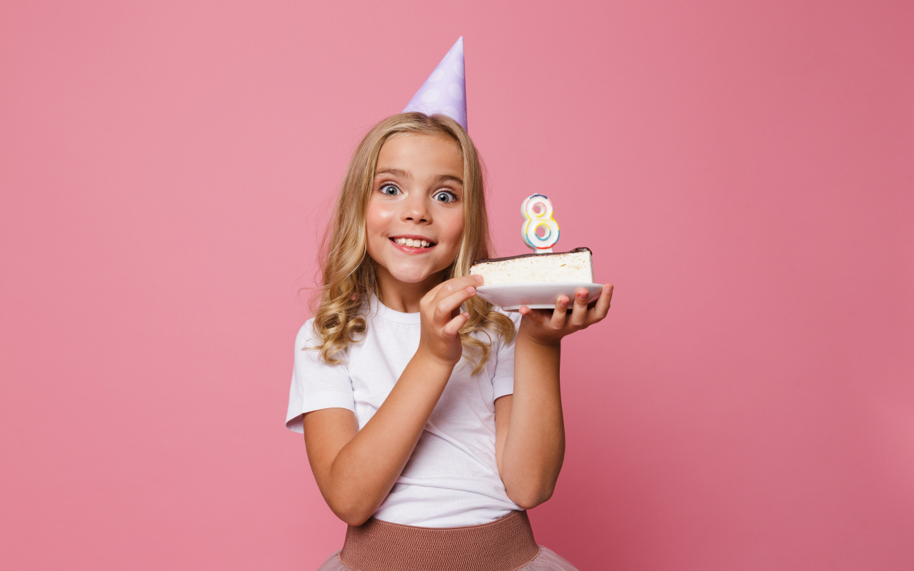 Милая девочка отмечает день рождения на розовом фоне