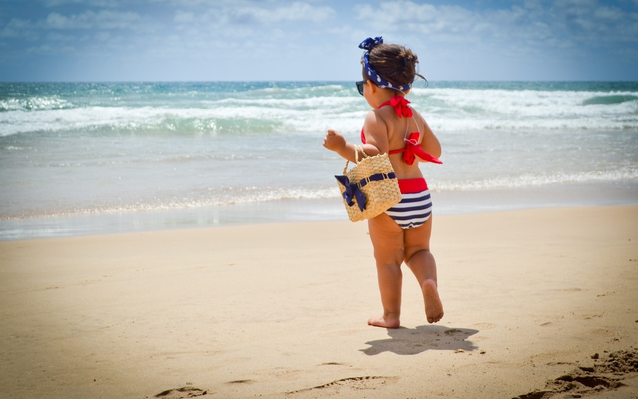 Модная маленькая девочка с сумочкой на берегу моря