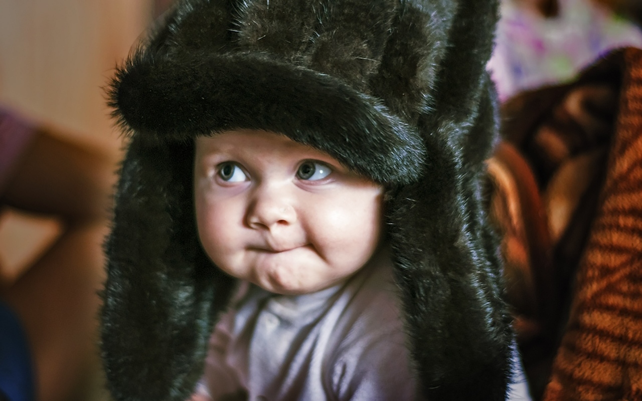 Смешной ребенок в черной меховой шапке