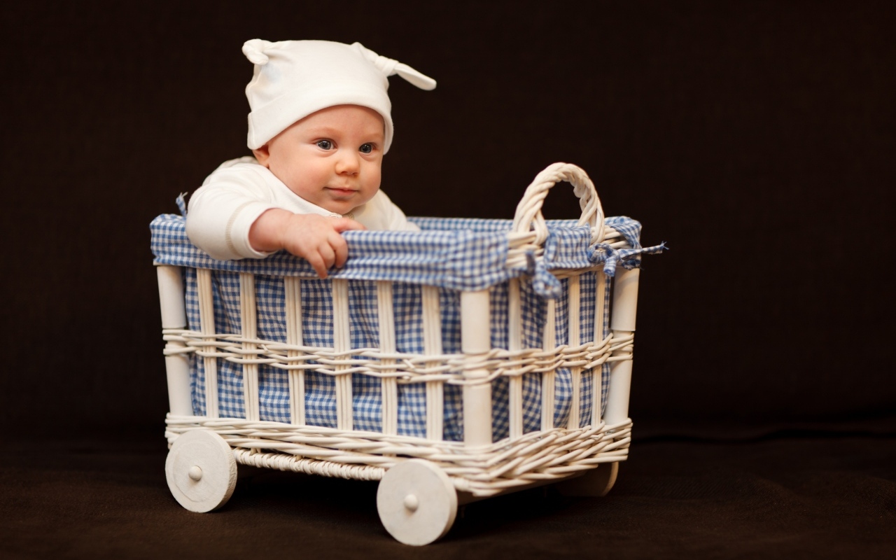 Маленький ребенок в колыбели на коричневом фоне