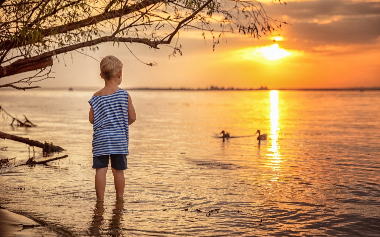 Маленький мальчик в тельняшке у озера на закате