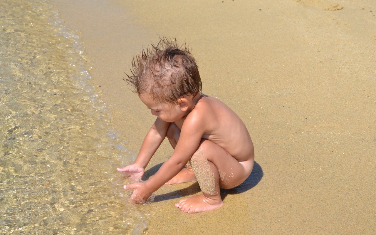 Маленький мальчик на пляже у моря на песке