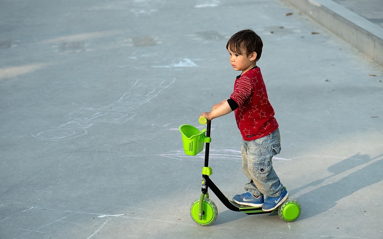 Маленький мальчик с зеленым самокатом