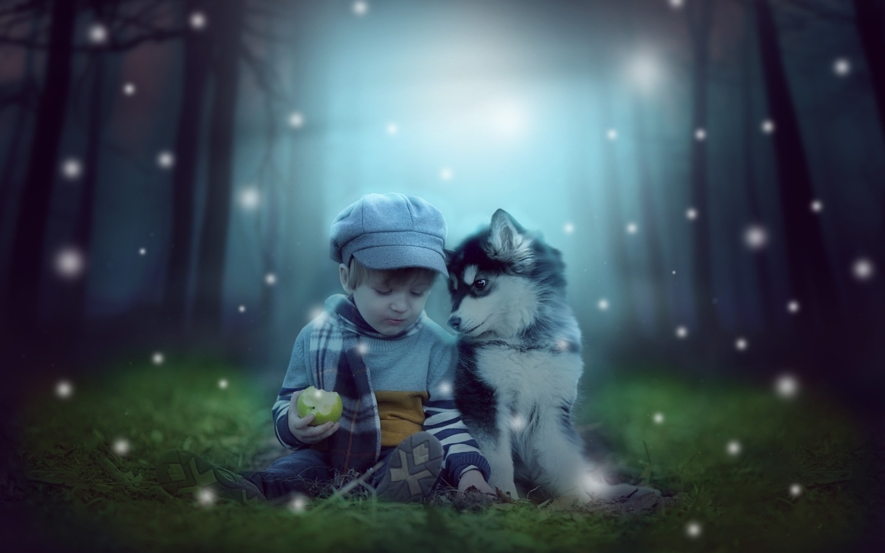 Маленький мальчик с щенком сидят на траве в лесу