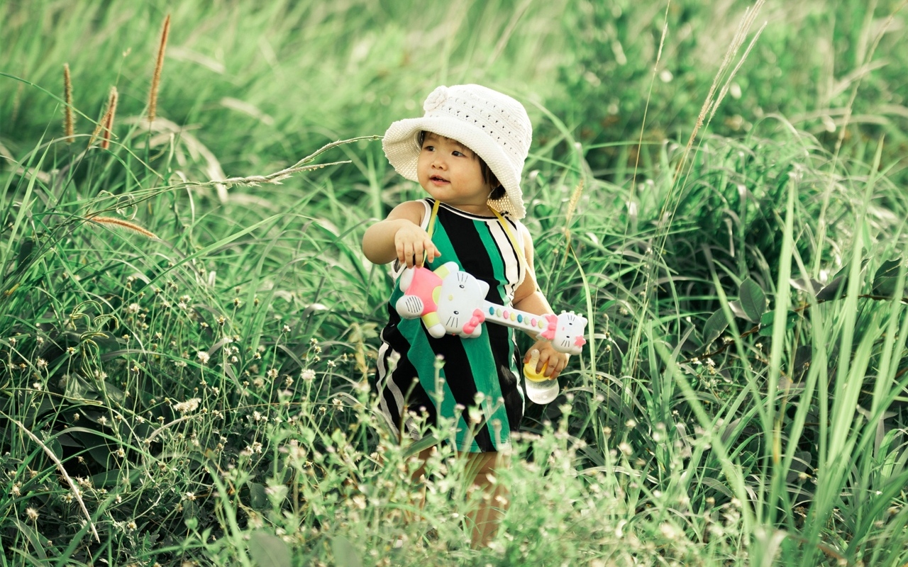 Маленькая девочка с игрушечной гитарой в траве