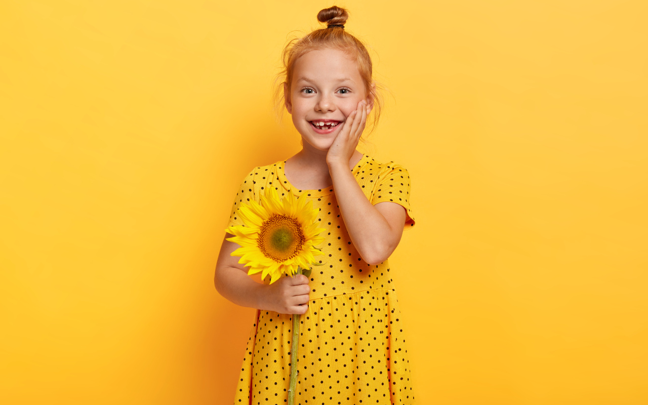 Маленькая рыжеволосая девочка с подсолнухом в руках