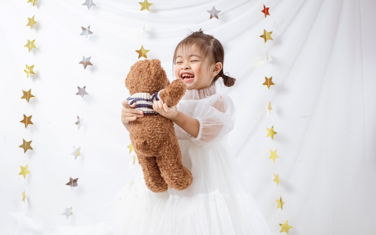 Улыбающаяся девочка азиатка с игрушечным медведем