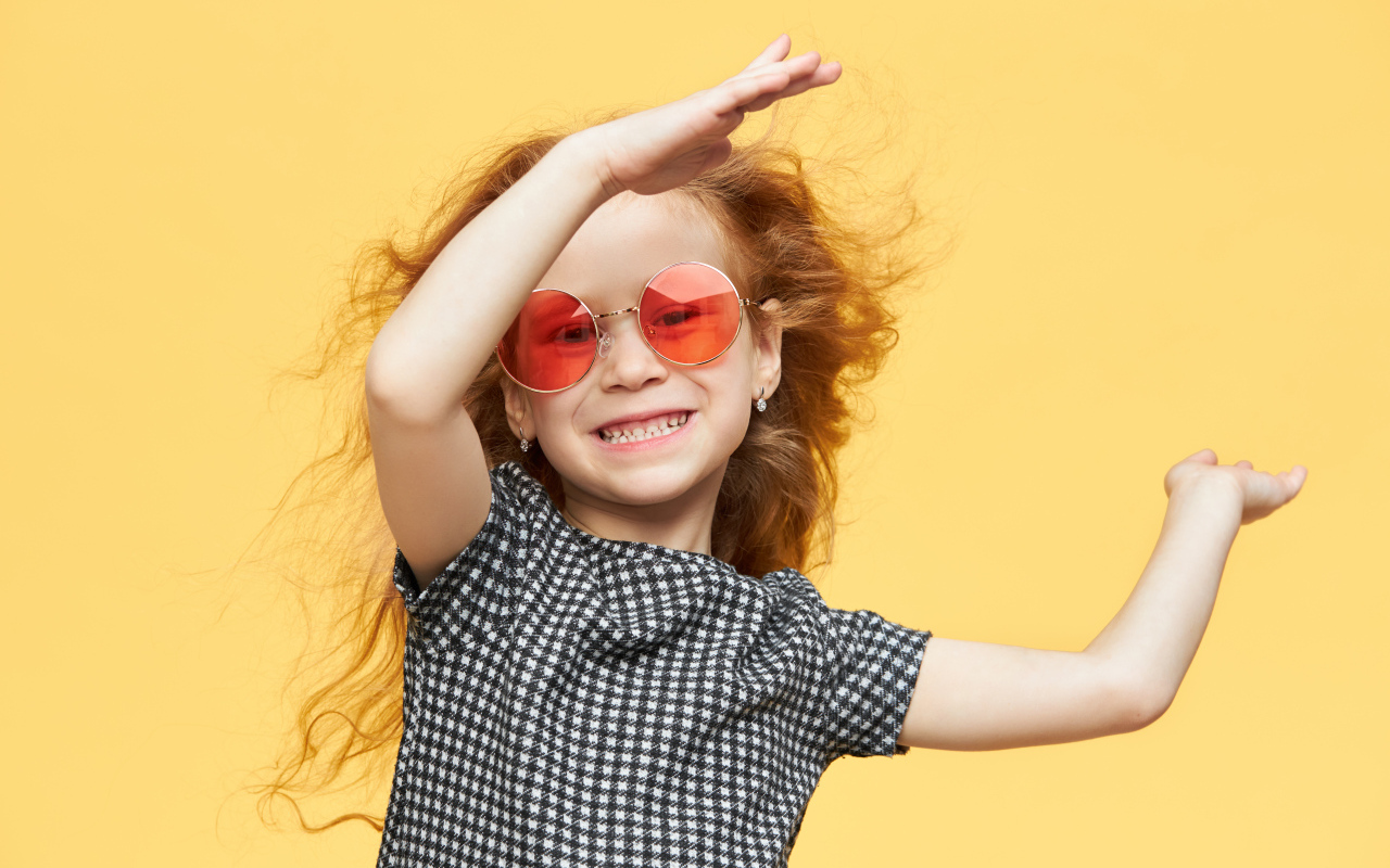 Улыбающаяся рыжеволосая девочка в очках