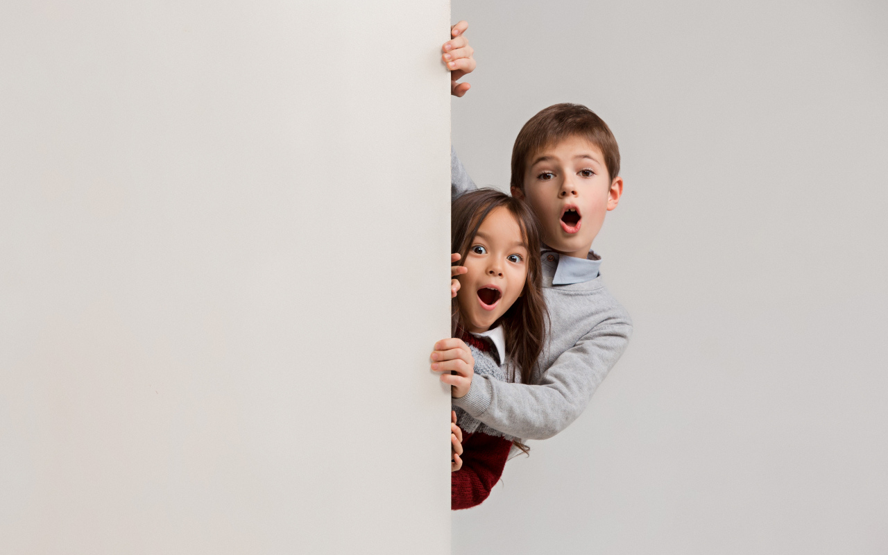 Удивленные дети выглядывают из-за угла
