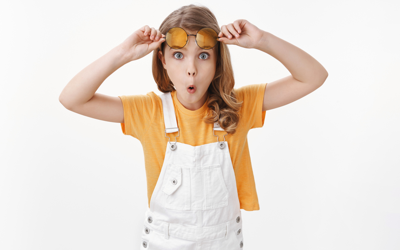 Удивленная девочка в очках на белом фоне