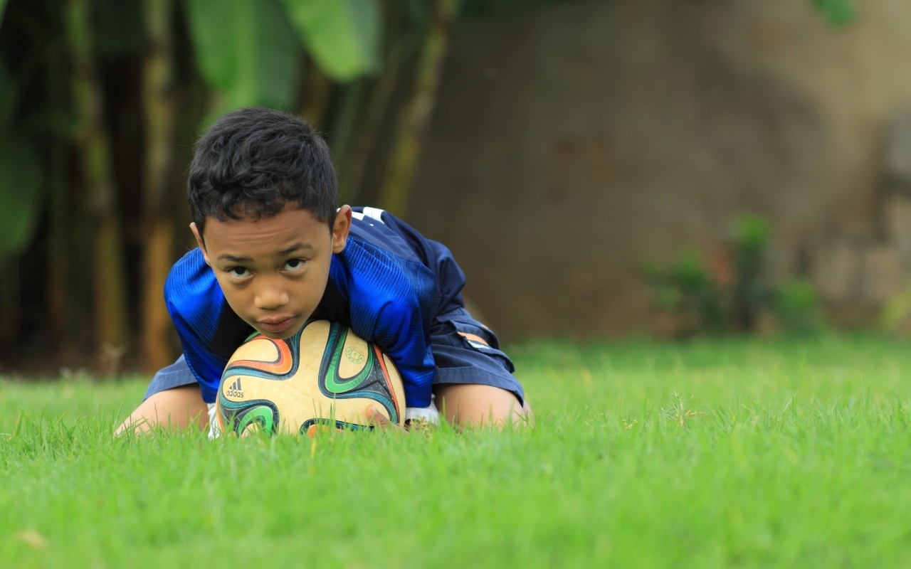 Мальчик юный футболист с мячом на поле