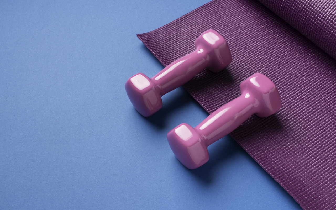 Розовые гантели и коврик на голубом фоне