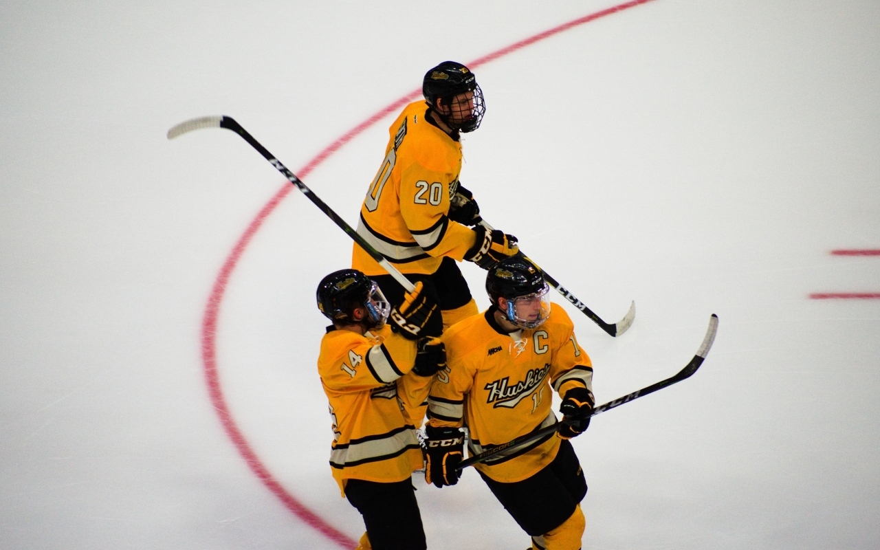 Три хоккеиста с клюшками на льду