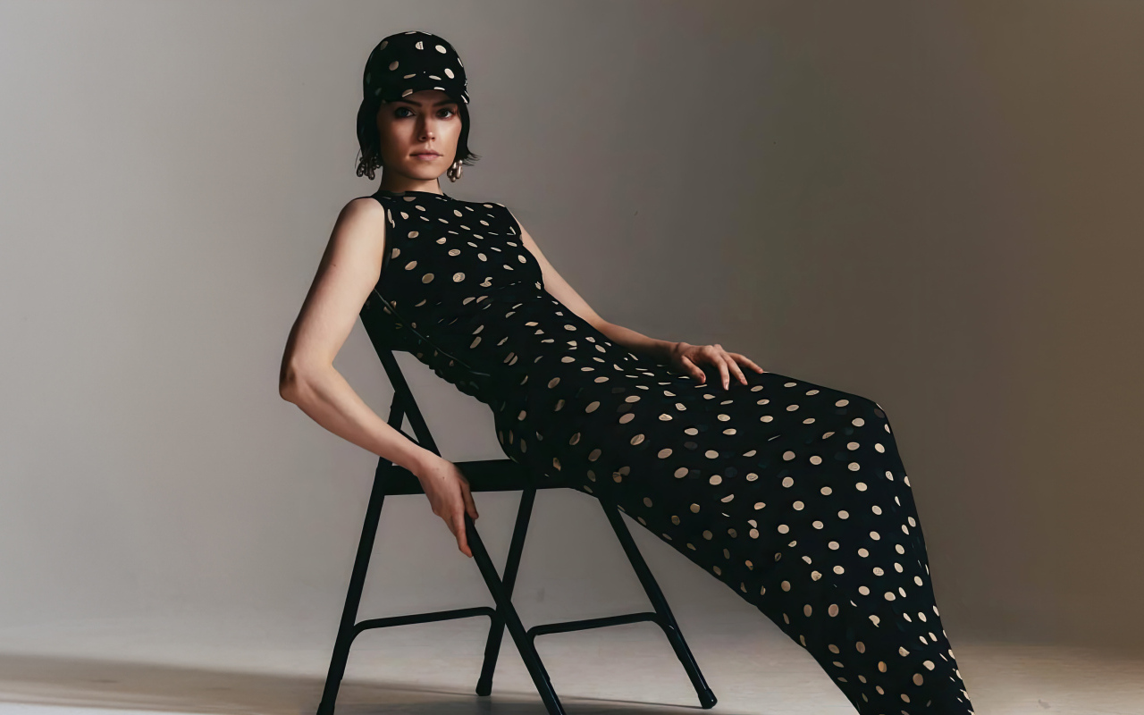 Актриса Дейзи Ридли в черном платье сидит на стуле