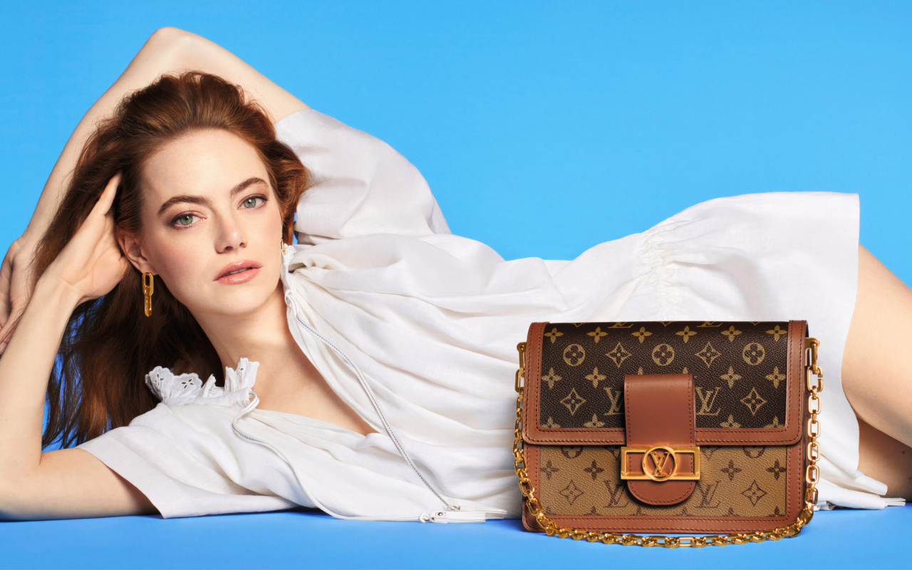 Актриса Эмма Стоун с сумочкой Louis Vuitton на голубом фоне