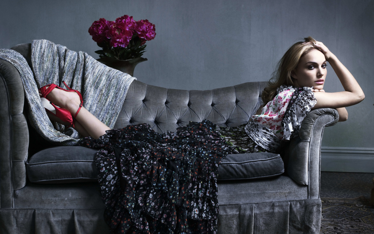 Актриса Натали Портман в платье лежит на сером диване
