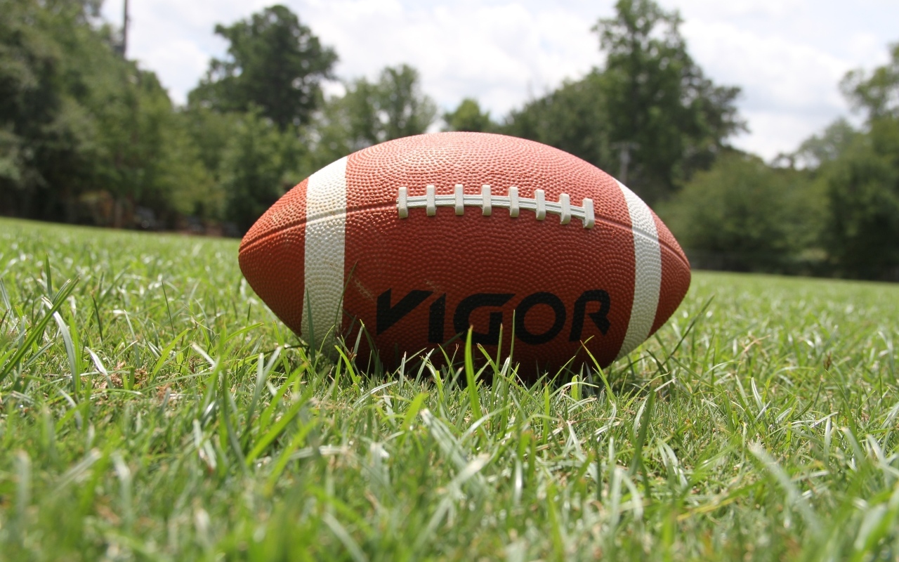 Мяч для американского футбола на зеленой траве 