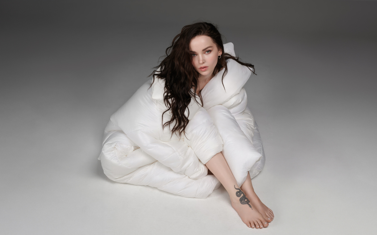 Красивая брюнетка Дав Кэмерон в белом костюме на сером фоне