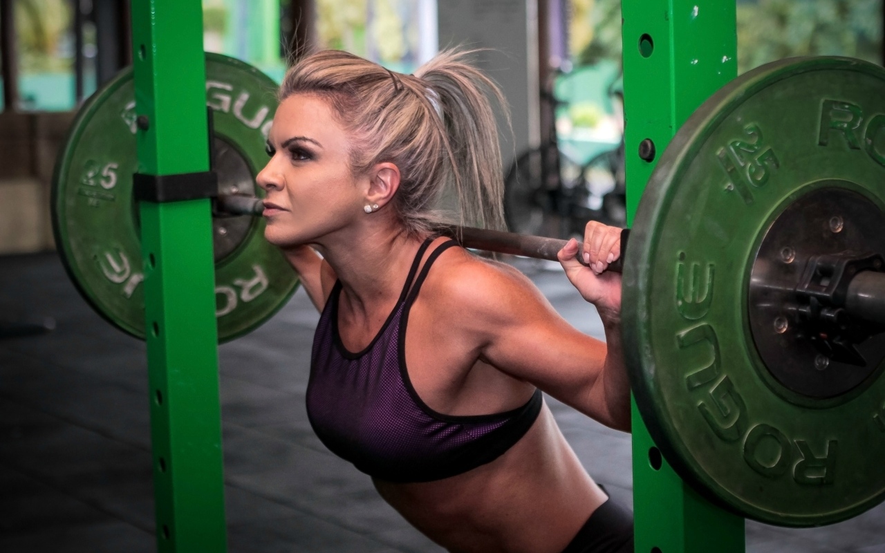 Сильная спортивная девушка поднимает штангу