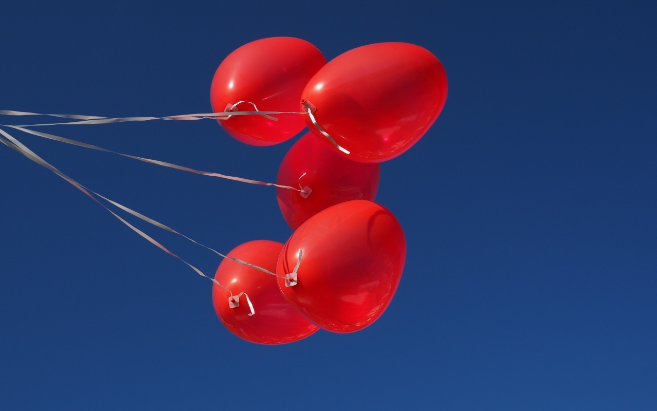 Красные воздушные шары на нитке на фоне голубого неба