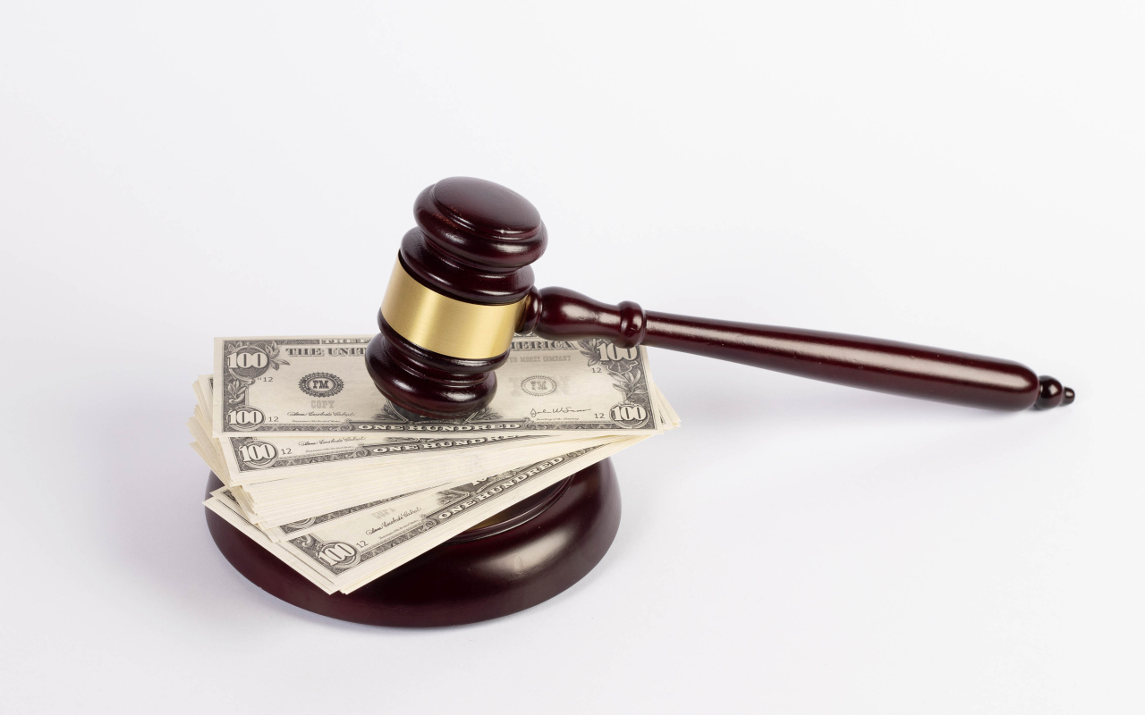 Молоток судьи и пачка долларов на белом фоне