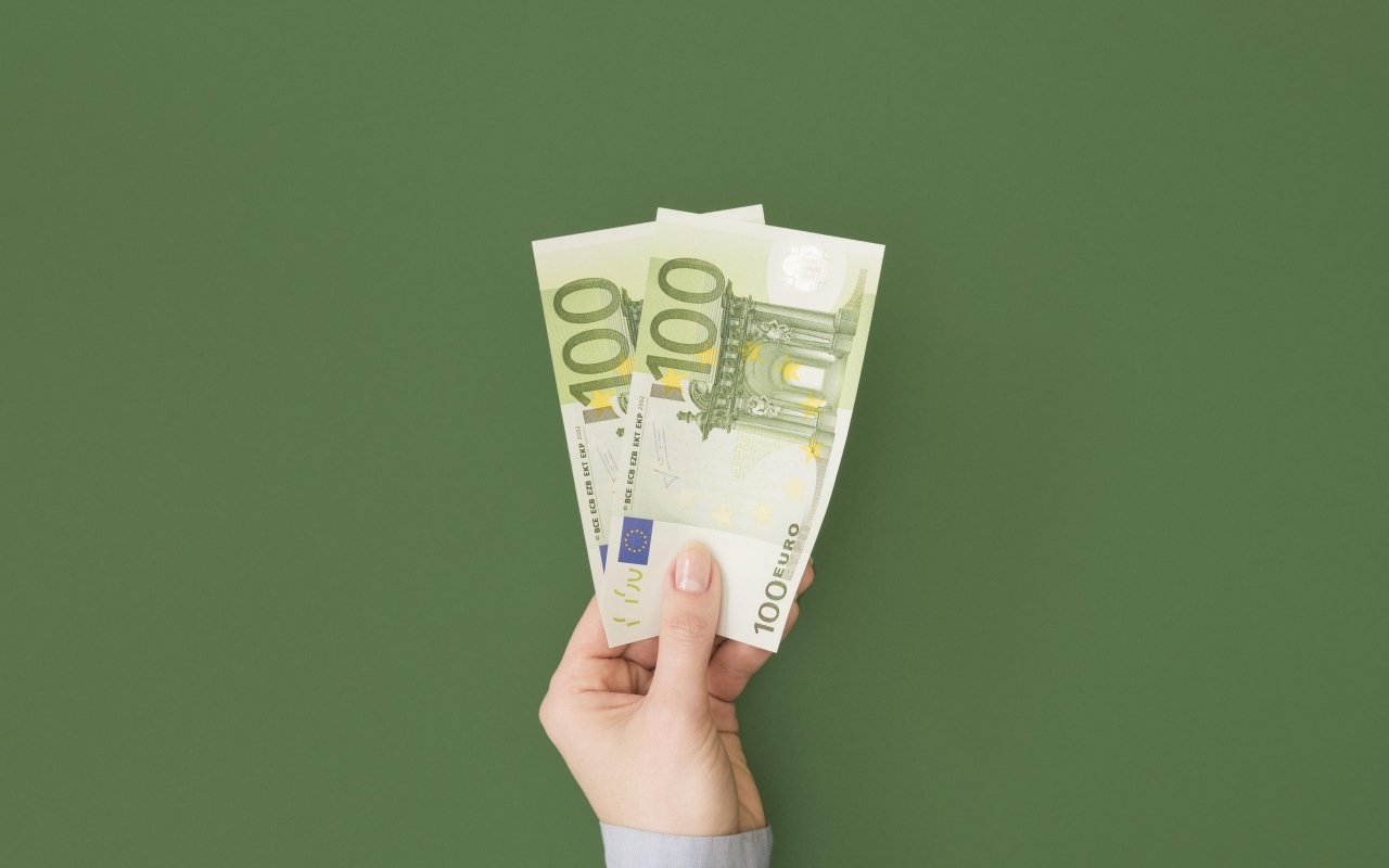 Две купюры по сто евро на зеленом фоне