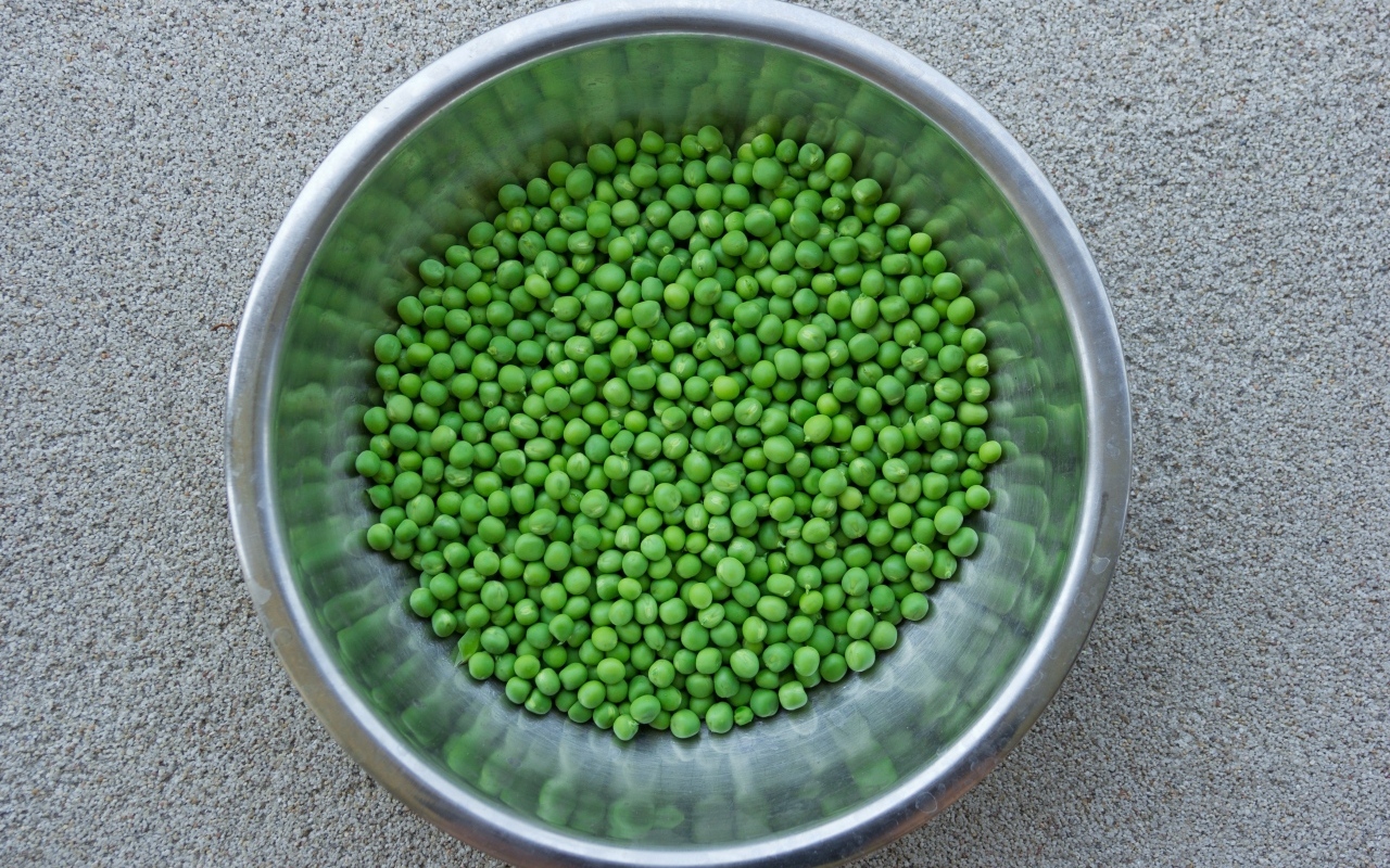 Зеленый горошек в жестяной миске на столе