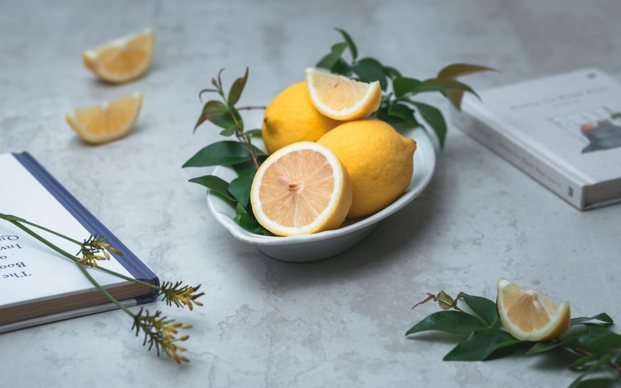 Лимон с зелеными листьями на столе с книгами