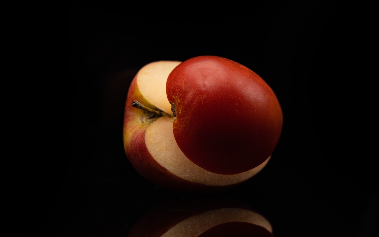 Разрезанное на половинки красное яблоко на черном фоне