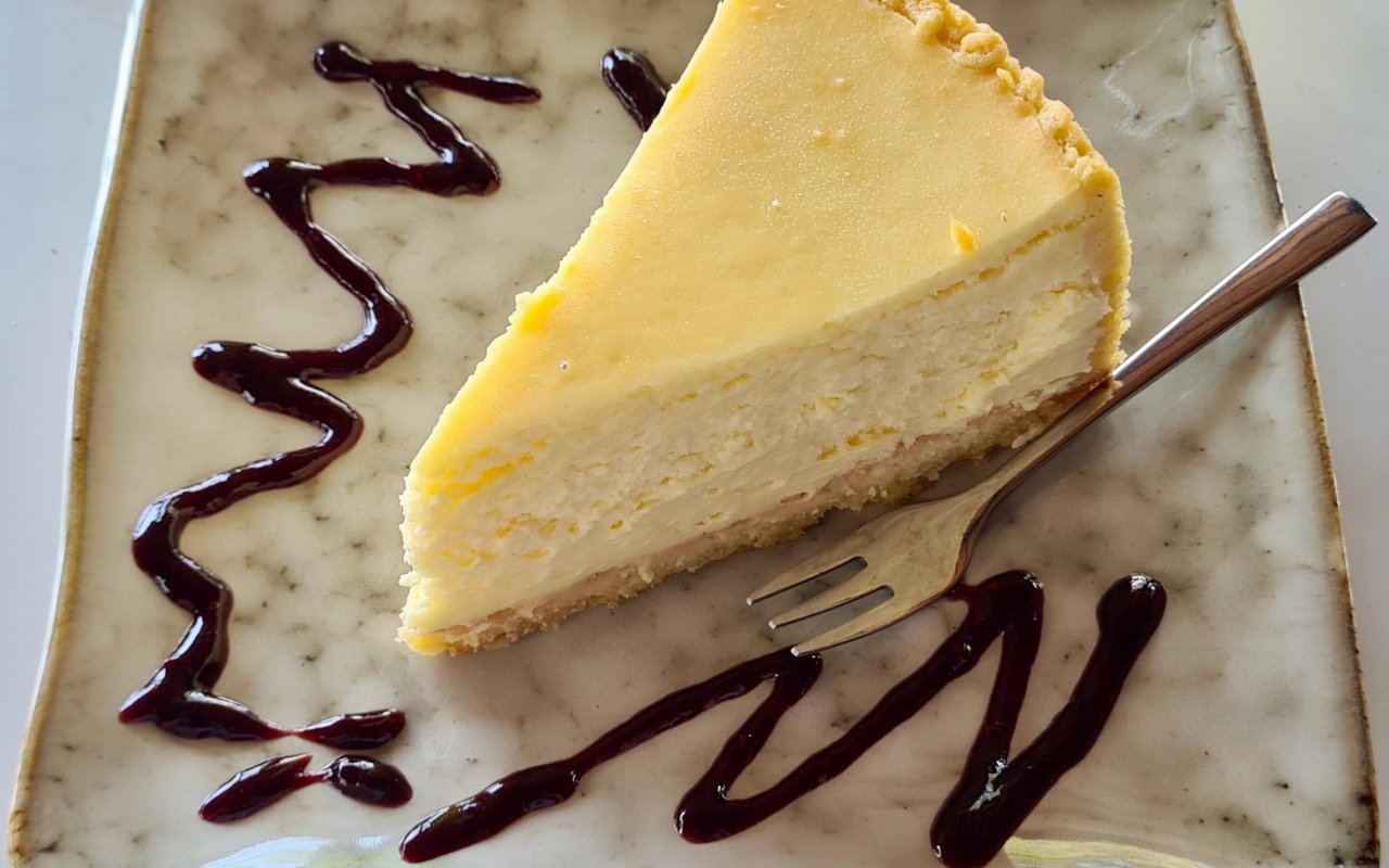 Кусок чизкейка с шоколадным топпингом на тарелке