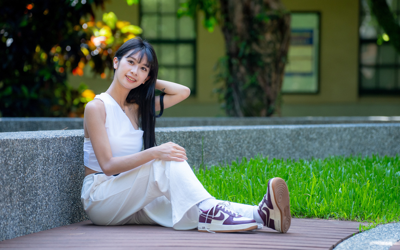 Девушка азиатка в белой костюме сидит на земле